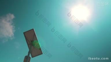 在蓝天和阳光交替的背景下，低角度拍摄装有太阳能电池的路灯
